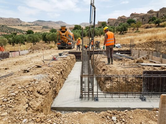 Strato di magrone sul fondo dello scavo di fondazione con le gabbie di armatura posate sui distanziatori, pronte per il getto del calcestruzzo strutturale.
